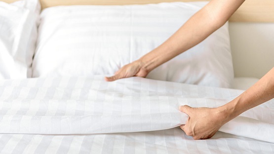 woman making bed sheets look beautiful folded
