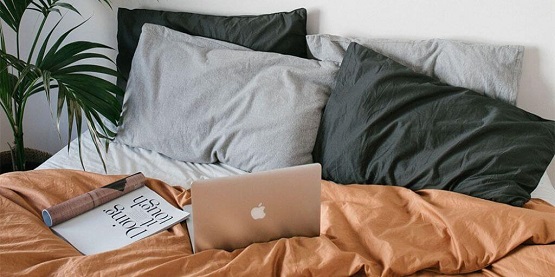 laptop and magazine on bed with nice sheets