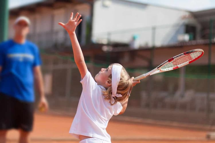 Little girl with tennis raquet in hands