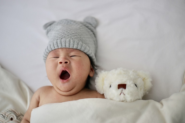 picture of a baby sleeping beside a plush toy covered with blanket 