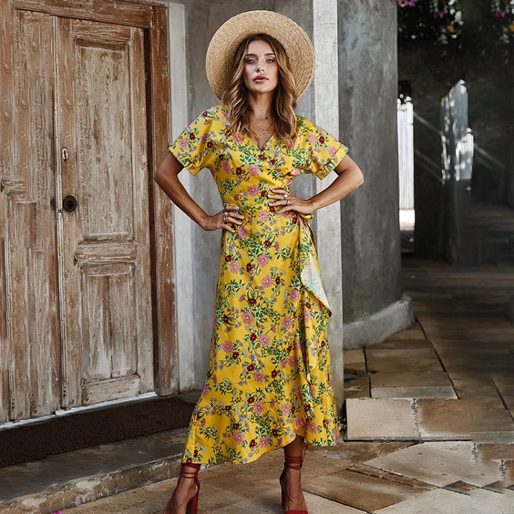 picture of a woman in yellow floral maxi dress and a hat standing in front a wooden door