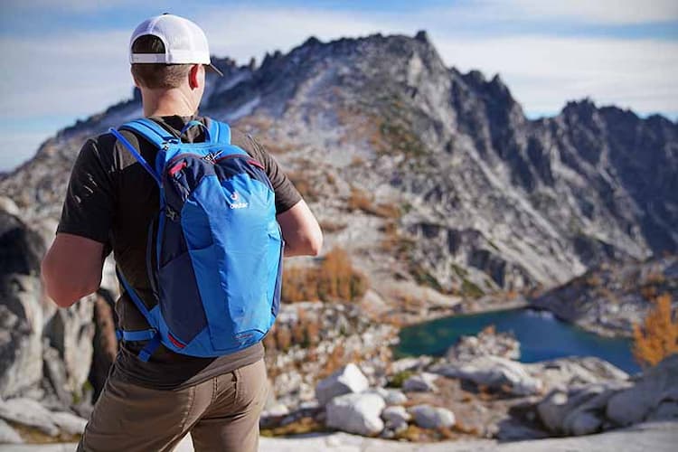 Back view of hiker wearing daypack and front view of mountain