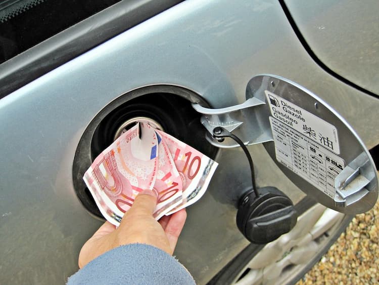 A person putting some 10 euro notes in their cars fuel tank