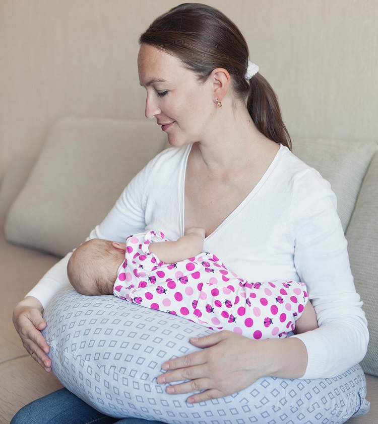 picture of a woman nursing an infant on a baby feeding pillow 