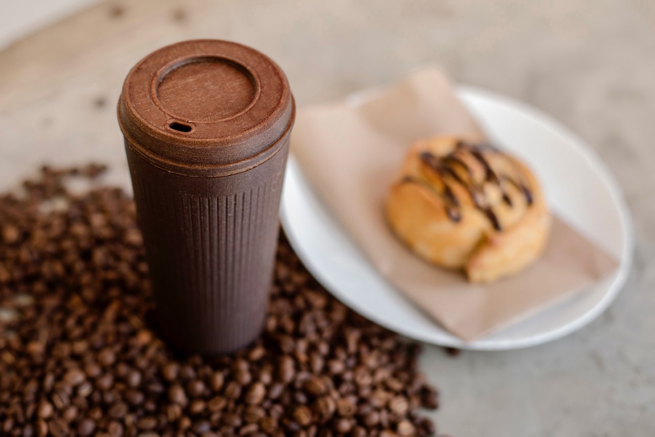 coffee transport cup with coffee beans around and cookie
