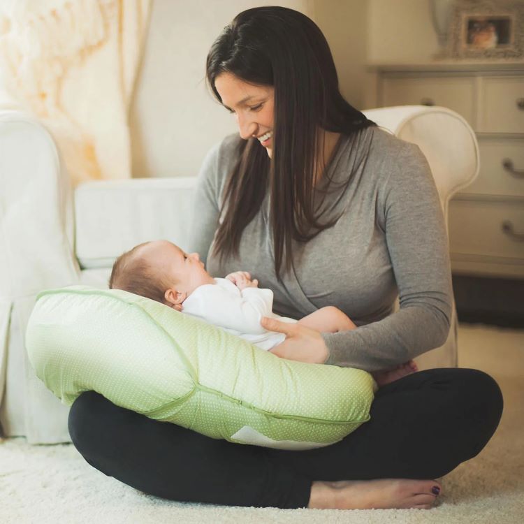woman holding her baby with nursing pillow