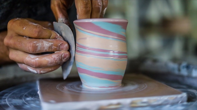 potter sculpting a coloured ceramic vase