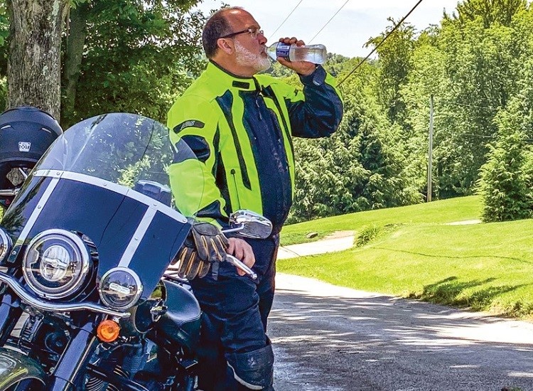 Man drinking water by the motorcycle